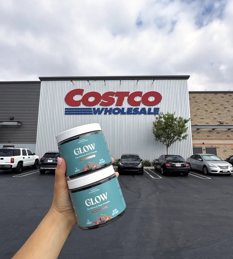 Two jars of Akasha Superfoods Glow held up outside a Costco Wholesale warehouse