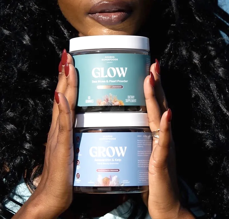 Akasha Superfoods Glow and Grow gummy jars held up to the face