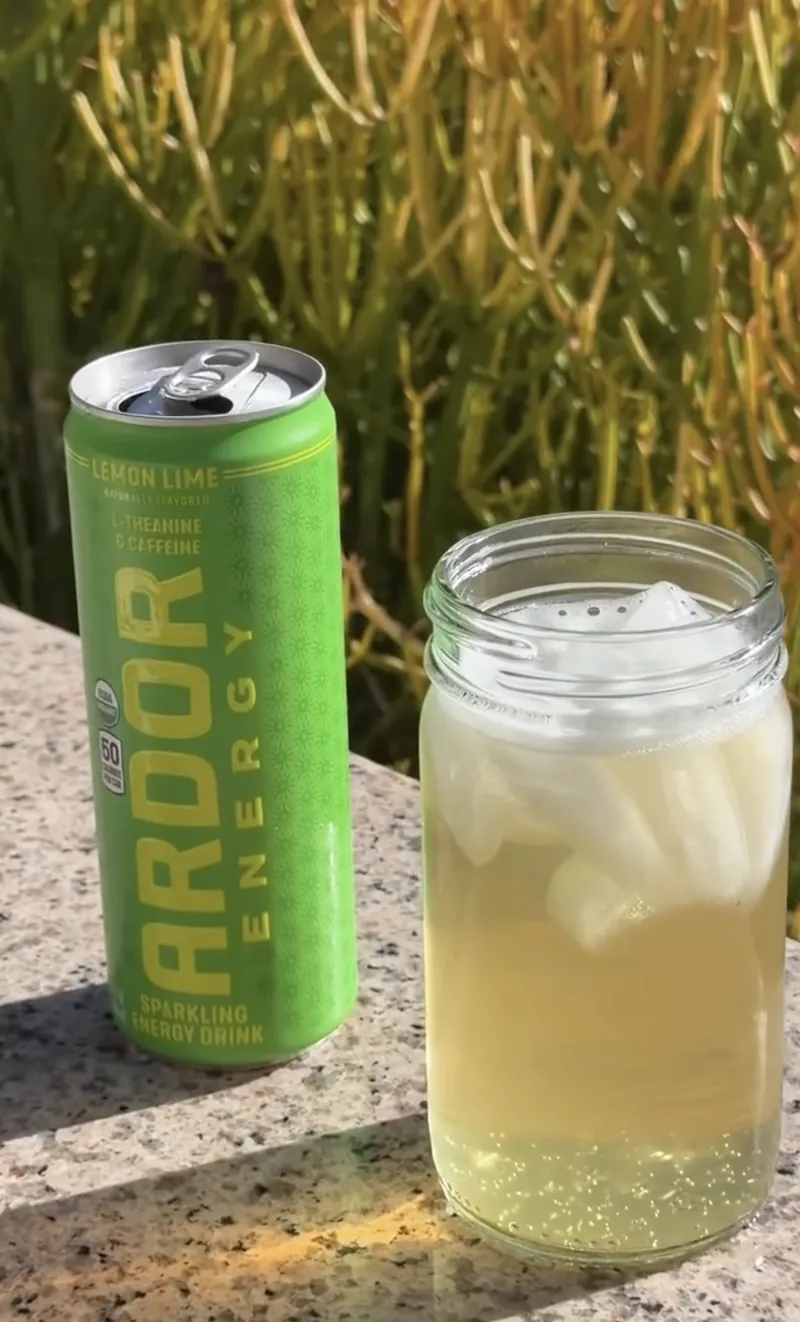 An open Ardor Energy Lemon Lime can beside an iced glass in the sun