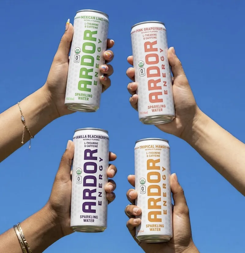 Four Ardor Energy sparkling water cans raised against a blue sky
