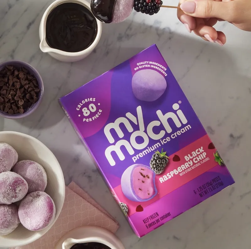 A My/Mochi Black Raspberry Chip ice cream box on marble with mochi and chocolate