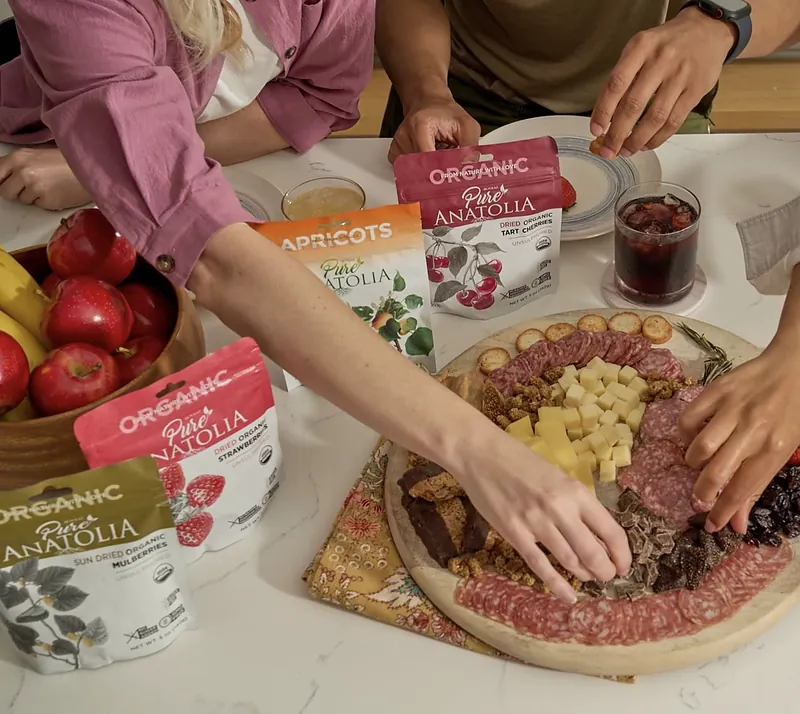 Pure Anatolia dried organic tart cherries, apricots, strawberries and mulberries beside a snack board